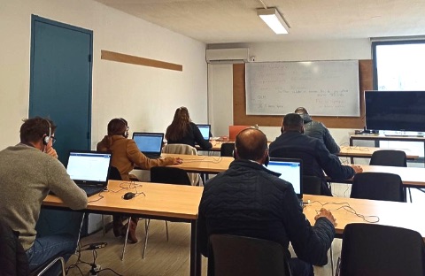 Personnes qui passent leur test d'évaluation de français dans une classe sur des ordinateurs.